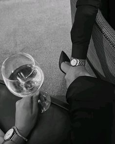 a person holding a wine glass in their hand while sitting on the floor next to a chair