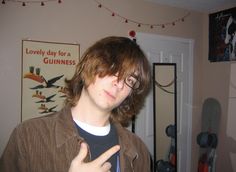 a young man wearing glasses making the peace sign