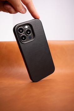 a person touching the back of an iphone 11 pro with their finger on top of it