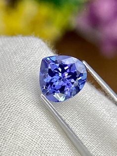 a blue diamond sitting on top of a piece of white cloth next to a flower