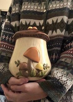 a person holding a ceramic pot with mushrooms on it