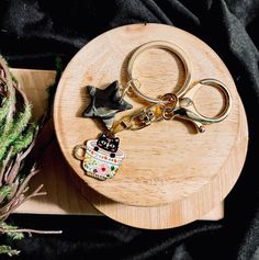 a pair of scissors and a keychain sitting on a wooden tray next to a plant