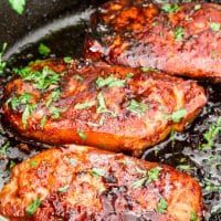 some meat is cooking in a pan with sauce and parsley on the top,