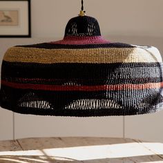 a multicolored woven lamp shade hanging from a ceiling fixture in a living room