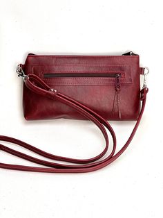 stylish hands free cross body bag with long strap and  wristlet strap *  can be used as evening clutch or cross body *  deep burgundy red rich leather *  zipper pocket on outside rear and 1 slip pocket inside *  fully lined with complimentary fabric *  silver hardware and ykk zipper closure *  measures 6 inches by 9 inches with gusset bottom *  53 inch strap          can be shortened Burgundy Crossbody Bag With Cell Phone Pocket, Burgundy Crossbody Bag With Zipper Closure, Burgundy Evening Bag With Zipper Closure, Burgundy Leather Shoulder Bag With Mobile Phone Pouch, Burgundy Leather Shoulder Bag With Mobile Phone Holder, Leather Shoulder Bag With Mobile Phone Bag In Burgundy, Burgundy Leather Shoulder Bag With Phone Holder, Burgundy Soft Leather Crossbody Shoulder Bag, Burgundy Crossbody Shoulder Bag With Removable Pouch