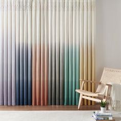 a living room with a chair, rug and window covered in multicolored curtains