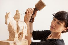 a woman is working on a sculpture that looks like a horse with a wooden handle