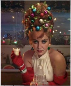 a woman with christmas decorations on her head sitting at a table in front of a window