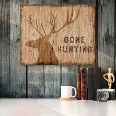 there is a wooden sign that says gone hunting next to some books and a camera