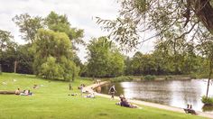 many people are sitting on the grass next to a river and some have fallen asleep