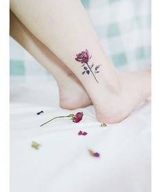 a woman's foot with a rose tattoo on her left ankle and pink flowers on the other side