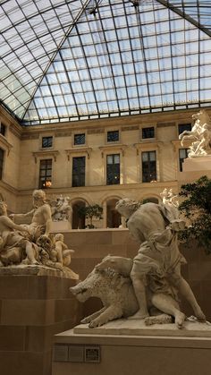 the inside of a building with statues and glass roof