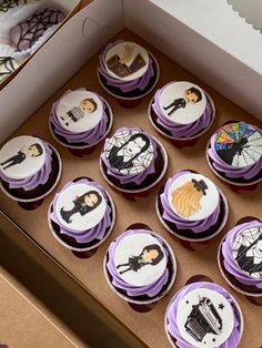 twelve decorated cupcakes in a box with purple icing and white frosting