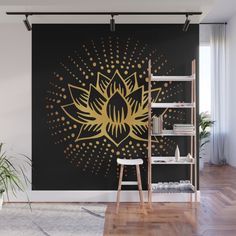 a black and gold wall mural with a golden flower on the center, in front of a bookshelf