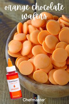 orange chocolate wafers in a wooden bowl with an orange dropper next to it