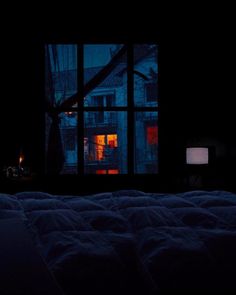 a bed in a dark room next to a window with the night light on it