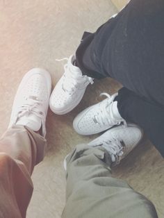 two people standing next to each other on the floor with their feet up in front of them