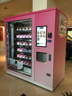 a pink vending machine sitting in the middle of a mall filled with lots of drinks