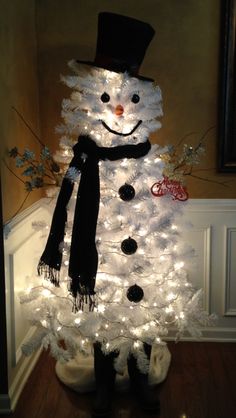 a white christmas tree decorated with lights and a snowman