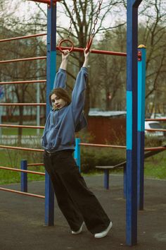 a young boy is playing on a playground with his hands in the air while holding onto an exercise ring