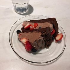 a piece of chocolate cake with strawberries on it and a glass of water next to it