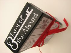 a close up of a book with a red ribbon tied around it and the cover has writing on it