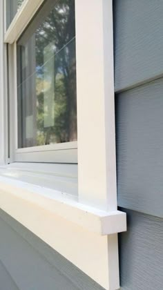 a close up of a window on the side of a house with white trim and windowsill