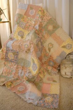 a blanket is laying on the floor next to a jar and glass vase with flowers