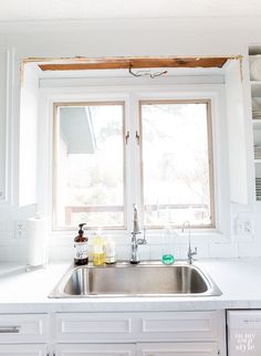 a kitchen sink under a window next to a stove top oven and dishwasher