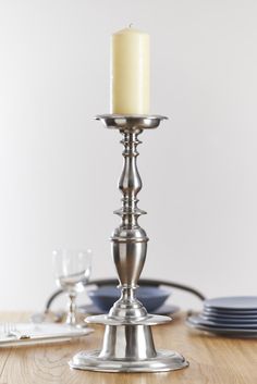 a lit candle is sitting on a table with plates and silverware in the background