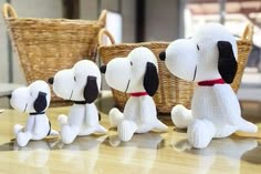 three stuffed dogs sitting next to each other in front of a basket on a table