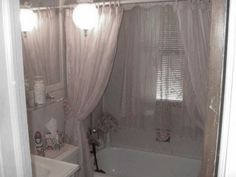 a bathroom with a sink, toilet and bathtub covered in white curtained curtains