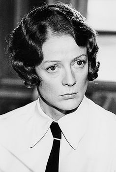 black and white photograph of woman in dress shirt and tie looking to the side with serious expression