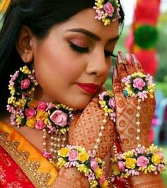 a woman with flowers on her head and hands in front of her face, wearing jewelry