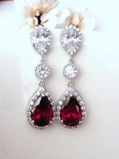 This classy earring features a large halo dark red garnet peardrop cubic zirconia ( 20 x 14 mm, not including the loop) with multi small cubiz zirconias around it, dangle from a round cubic zirconia connector with a white gold plated peardrop cubic zirconia post earring, the ear post is made of sterling silver. Size: 4.4 x 1.4 cm Note: New design on post earring, it has many small cubic zirconia around on the edge, it is slightly larger than the one used in my other earrings that hasn't had the cubic zirconia on the edge. Matching necklace is also available: Listing: https://www.etsy.com/listing/176745273/wedding-bridal-necklace-high-quality **NOTE: CUBIC ZIRCONIA HAS MANY DIFFERENT GRADES, AND ALL THE CUBIC ZIRCONIA USED IN MY DESIGN IS OF THE HIGHTEST QUALITY. IT SPARKS LIKE DIAMOND AND Classy Earrings, Beautiful Tiaras, Large Earrings, Bridal Necklace, Matching Necklaces, Red Garnet, Bridesmaid Jewelry, Bridal Earrings, Dark Red