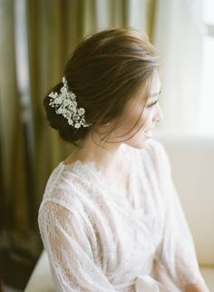 a woman sitting on a couch wearing a white dress with flowers in it's hair