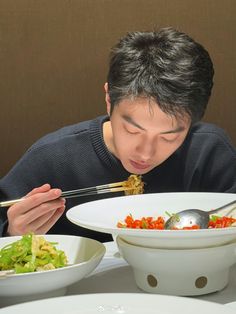 a young man eating from a bowl with chopsticks