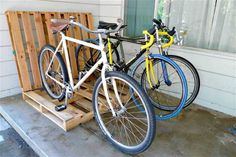 two bikes parked next to each other on a wooden pallet in front of a house