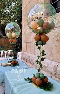 an outdoor table with balloons and greenery on it