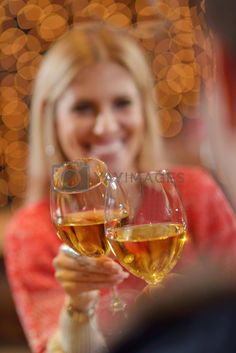 a woman holding up two glasses of wine