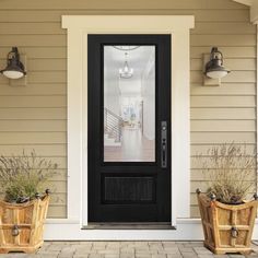 two planters with plants are sitting in front of a door on a house's porch