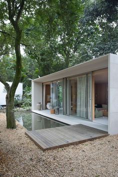 a house that is in the middle of some trees and gravel with water running through it