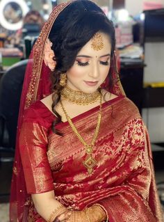 a woman in a red and gold sari is looking down at her wrist bracelet