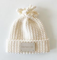 a white knitted hat with a label on it that says daisy farm cauts