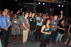 a group of people standing around each other in a room with lights on the ceiling