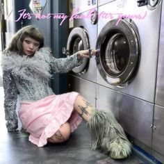 a woman in a pink dress is next to a washing machine and her dog sits on the floor