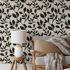 a living room with black and white wallpaper, two lamps and a chair in front of the couch