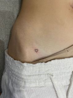 a woman's stomach with a small heart tattoo on it