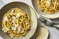 two bowls filled with pasta and garnished with parmesan cheese on top