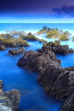 the blue water is surrounded by large rocks